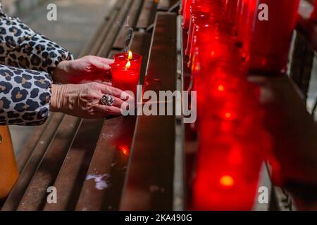 Barcelone - Espagne, 10 avril 2022: Main de la femme de croyance méconnaissable dans l'église tenant une bougie dans la cathédrale de Barcelone (Espagne). Banque D'Images