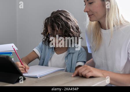 Lunettes de mère et de petit fils étudier en ligne sur tablette à la maison ensemble de la leçon, préparer les devoirs Banque D'Images