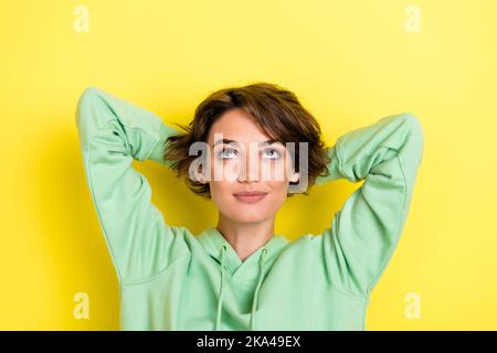 Photo portrait de la belle jeune femme bras derrière la tête regarder l'espace vide porter ensemble vert tendance isolé sur fond jaune Banque D'Images