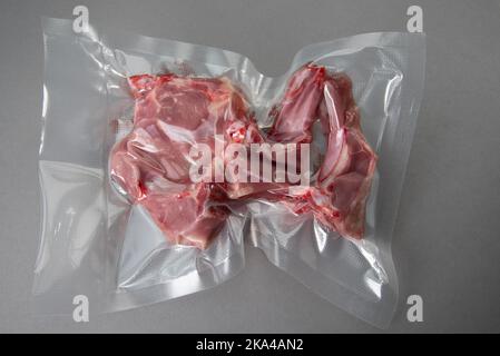 Côtelettes d'agneau emballées sous vide scellées pour une cuisson sous vide sur fond gris dans la vue de dessus Banque D'Images