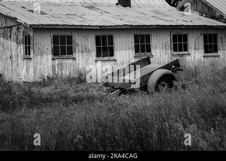 Une photo en échelle de gris d'un ancien chariot en bois et d'une grange aux intempéries dans l'Indiana Banque D'Images