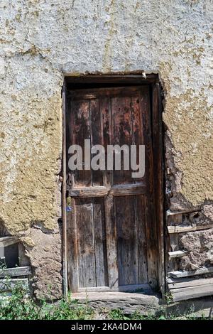 Une verticale d'une porte en bois usée et abîmée d'une maison rurale semi-effondrée Banque D'Images