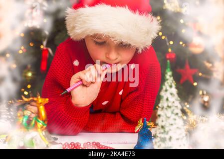 Petit garçon à Santa Hat écrit la lettre au Père Noël Banque D'Images