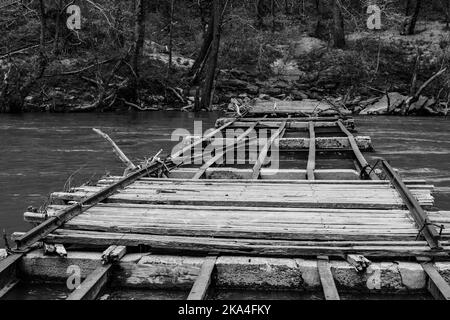 Une photo en niveaux de gris d'un pont en bois cassé sur la rivière Big South Fork Banque D'Images