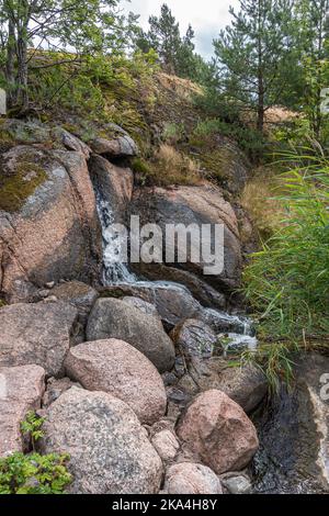 Finlande, Kotka - 18 juillet 2022 : parc Sopokanlahti, parc aquatique et lac. L'eau coule sur des roches brunes comme des flancs de colline verte avec des arbres et des plantes Banque D'Images