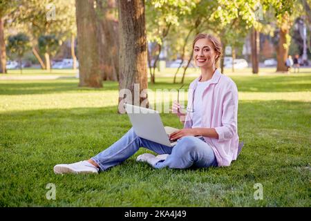 Femme d'affaires assise dans un parc d'été avec un ordinateur portable personne d'affaires travaillant à distance. Outdoor succès européen de caucasien femme freelance faire appel vidéo enseignant étude travail en ligne leçons Banque D'Images