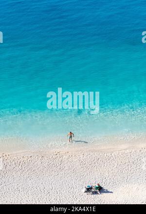Une belle plage de sable avec de l'eau cristalline avec un couple appréciant leurs vacances. Banque D'Images