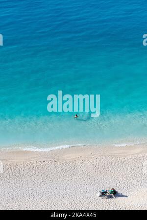 Une belle plage de sable avec de l'eau cristalline avec un couple appréciant leurs vacances. Banque D'Images