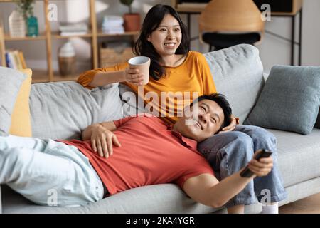 Les amoureux chinois détendus se retrouveront à la maison, regardant la télévision Banque D'Images