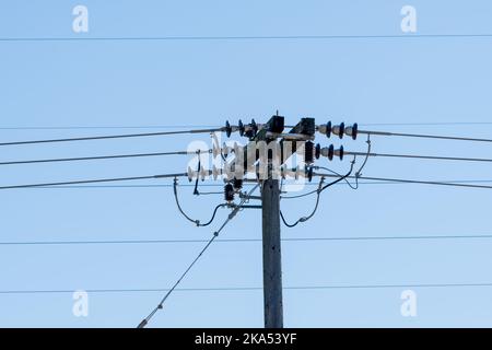 Gros plan d'une ligne aérienne de transport d'électricité sur un poteau en bois dans une zone rurale. Banque D'Images