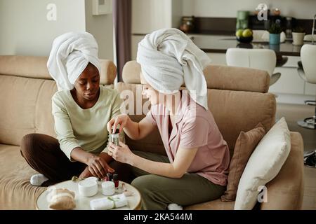 Portrait de deux filles avec des serviettes faisant la manucure tout en appréciant la beauté jour à la maison Banque D'Images