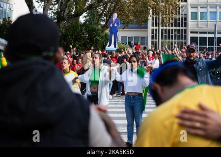 Porto, Portugal. 30th octobre 2022. Un groupe de partisans de Bolsonaro tient les mains pour prier pendant les élections à Porto. Des milliers de Brésiliens votent dans la ville de Porto, au Portugal, dans une atmosphère exubérante. Malgré la grande majorité des partisans de Lula, des renforts de police ont été nécessaires pour maintenir l'ordre. Crédit : SOPA Images Limited/Alamy Live News Banque D'Images