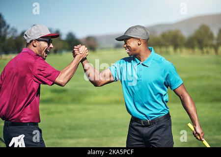 Grand frère de tir. Deux jeunes golfeurs gaies s'engageant dans une poignée de main après un grand tir sur le terrain de golf. Banque D'Images