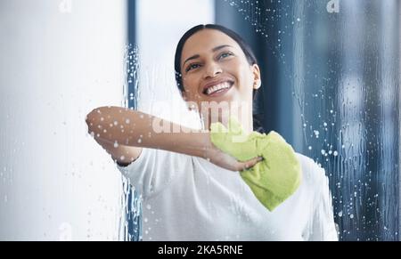 Nettoyage, verre et hygiène avec une femme noire à l'aide d'un chiffon ou d'un chiffon tout en essuyant une fenêtre dans un bureau. Nettoyant, concierge ou femme de ménage lave un Banque D'Images
