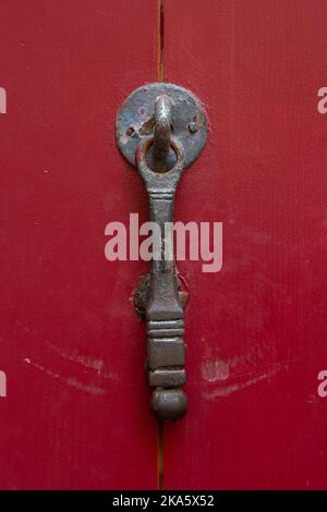 Vue rapprochée du knock de porte en laiton d'époque texturée isolé sur une ancienne porte en bois rouge vif, Montpellier, France Banque D'Images