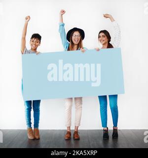 Tenez-vous debout pour quelque chose en qui vous croyez. Photo en studio d'un groupe de jeunes femmes portant un écriteau vierge et applaudisant sur un fond blanc. Banque D'Images