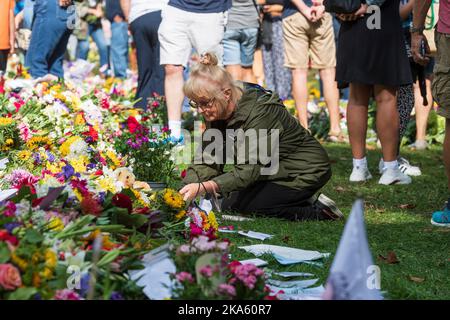 Une femme qui pose des fleurs sur les hommages floraux de Green Park, laissée par des bourneurs pour marquer la mort de la reine Elizabeth II. Green Park, Londres, Royaume-Uni. 11 septembre 20 Banque D'Images