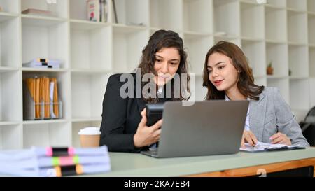 Deux femmes d'affaires ou comptables de la race blanche, millénaires, coopèrent, discutent et travaillent ensemble sur un rapport financier d'entreprise. Banque D'Images