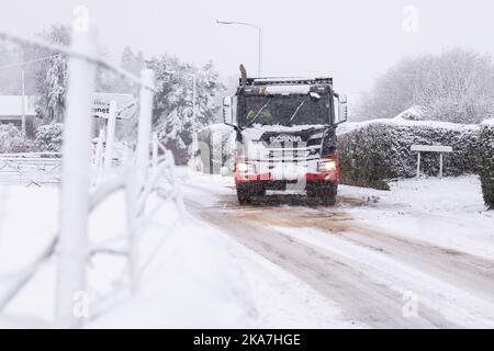 Les gravillons se répandent sur une route enneigée pour aider un camion à grimper une colline glissante, Killéarn, Stirling, Écosse, Royaume-Uni Banque D'Images