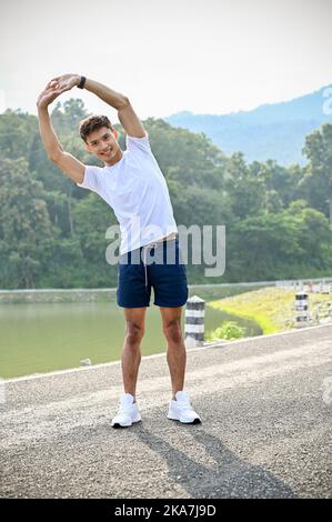Portrait, beau et athlétique jeune asiatique dans les vêtements de sport étirant ses bras, s'échauffe avant l'exercice en plein air. Entraînement, course, entraînement, hea Banque D'Images