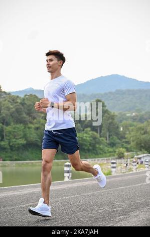 Portrait, belle tenue athlétique jeune homme asiatique dans des vêtements de sport se concentrant sur la course à l'extérieur le matin. Banque D'Images