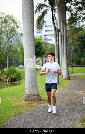 Portrait, beau et mettre en forme le jeune asiatique dans les vêtements de sport courir ou de jogging dans le parc de la ville le matin. Banque D'Images