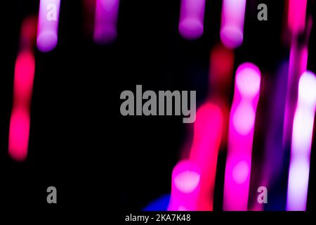 Les rayons lumineux au néon clignotent et s'allument en noir. Traînées claires couleur électrique sur fond noir. Banque D'Images