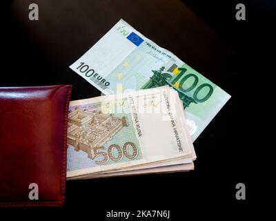 Bande de papier argent peering de portefeuille croates croates croates Kuna Kune Kunas billets et Euro européen euros fond noir Banque D'Images