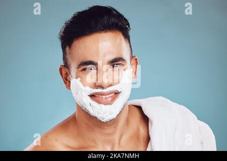 Visage, beauté et rasage avec un modèle homme en studio sur fond bleu pour le bien-être ou le toilettage. Portrait, soin de la peau et épilation avec un beau Banque D'Images
