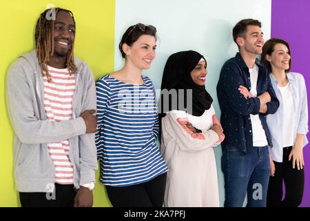 Divers adolescents utilisant des appareils mobiles tout en posant pour une photo en studio devant un arrière-plan coloré Banque D'Images