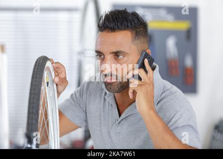 mécanicien de vélo au téléphone pendant la réparation de vélo Banque D'Images