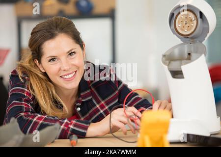 femme qui teste un appareil à l'aide d'un multimètre Banque D'Images