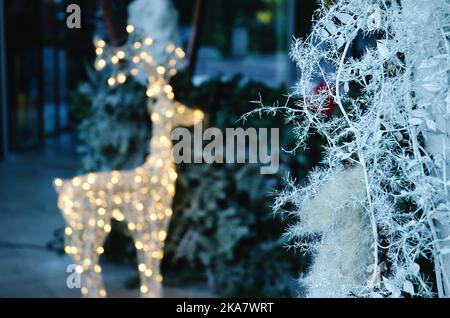 Extérieur du nouvel an et de Noël. Arbre de Noël décoré d'illuminations, guirlandes, jouets. Cerf néon jouet. Vue sur la ville. Banque D'Images