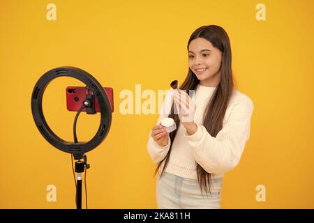 Une jeune fille blogger influenceur utiliser la lampe LED de selfie et smartphone sur trépied pour faire le tutoriel vidéo en ligne. Blog de beauté, présentation de cosmétiques de maquillage Banque D'Images