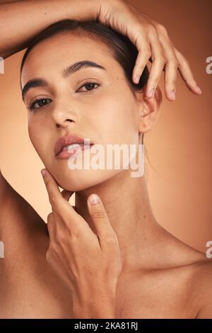 Portrait, soin de la peau et beauté avec une femme modèle touchant son visage en studio sur un fond beige. Mains, bien-être et luxe avec une femme posant à Banque D'Images