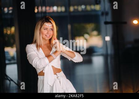 Portrait d'une fille souriante dans une robe blanche avec ses paumes clastées devant elle. Banque D'Images