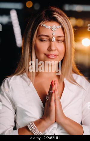 Portrait d'une fille souriante dans une robe blanche avec ses paumes clastées devant elle Banque D'Images