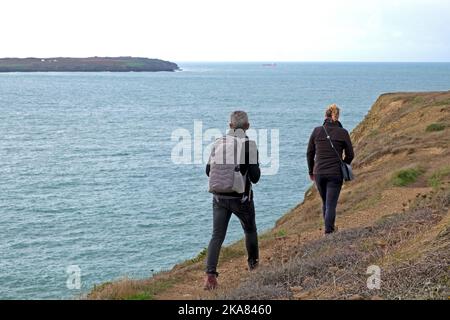 Vue arrière de deux personnes marchant le long du bord de la falaise sur le chemin de la côte du pays de Galles en automne Marloes Pembrokeshire Royaume-Uni Grande-Bretagne KATHY DEWITT Banque D'Images