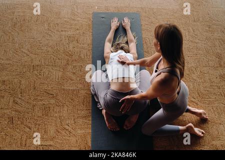 Exercices de yoga. Un entraîneur personnel enseigne à une femme des cours de yoga dans la salle de gym Banque D'Images