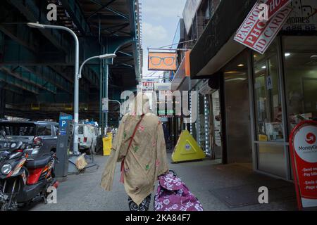 Une femme musulmane anonyme photographiée de derrière marche vers l'est sur Roosevelt Avenue à Jackson Heights, Queens, New York City Banque D'Images