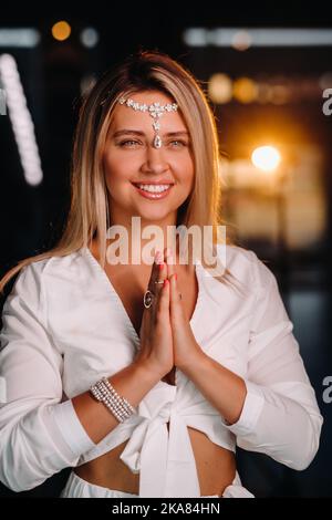 Portrait d'une fille souriante dans une robe blanche avec ses paumes clastées devant elle Banque D'Images