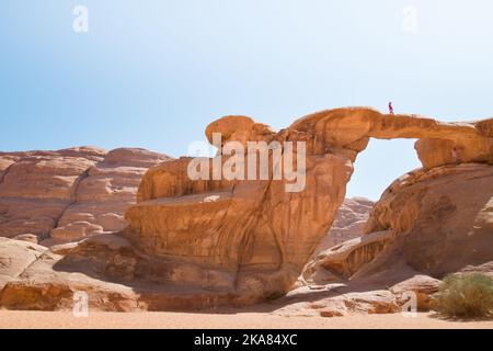 Vue du bas caucasien femme touriste stand sur le célèbre pont d'arche dans wadi rhum Desert pose et profiter de la vue panoramique des formations rocheuses pittoresques Banque D'Images