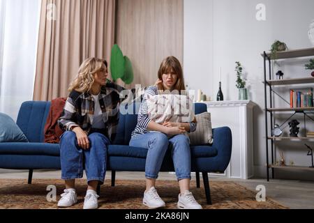Une femme mûre assise sur un canapé tente de calmer sa fille qui souffre de dépression. Je suis désolé, je ne voulais pas vous offenser Banque D'Images