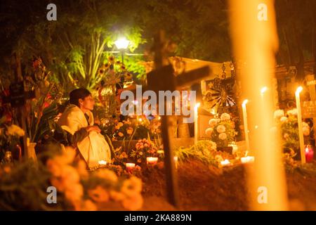 Oaxaca, Mexique. 31st octobre 2022. Une femme est assise à une tombe dans un cimetière éclairé et décoré de bougies. Chaque année sur 1 novembre, les habitants des communautés d'Oaxaca se rendent dans les cimetières pour tenir le réveil traditionnel aux tombes de leurs proches. Le jour de la Toussaint et de la Toussaint, le Mexique célèbre le jour des morts (Día de Muertos). Comme dans d'autres régions catholiques du monde, les morts sont commémorés - généralement à la tombe de parents décédés. Credit: Felipe Perez/dpa/Alay Live News Banque D'Images