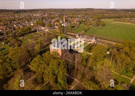 Château pittoresque de Moated Amerongen vu d'en haut entouré de jardins et parc avec la ville du village et les prairies de campagne en arrière-plan. Banque D'Images