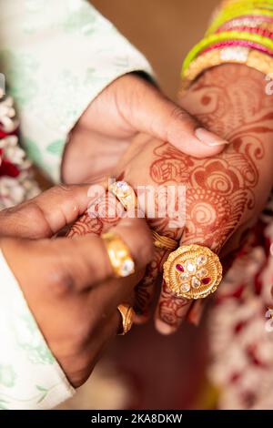 Gros plan des anneaux d'engagement échangés sur les mains avec le henné pendant un Indien traditionnel Banque D'Images