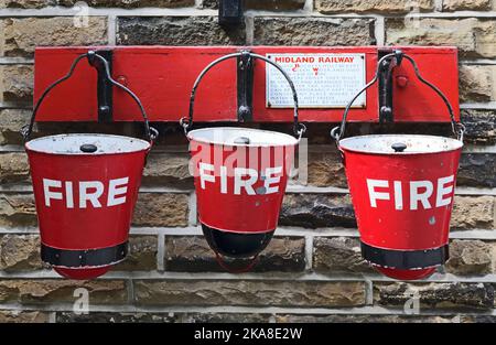 Vieux, Red Fire seaux sur des cintres, Ingce West gare, Keighley et Worth Valley Railway Banque D'Images