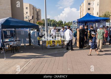 Les gens se rassemblent près des stands des partis politiques israéliens, à l'extérieur d'un centre de vote dans la ville de Harish, alors qu'Israël va voter pour 5th fois depuis 2019. Le stand à droite promeut le député Itamar Ben Gvir du parti sioniste religieux, et au centre - le parti religieux Sephardi (Shas) Banque D'Images