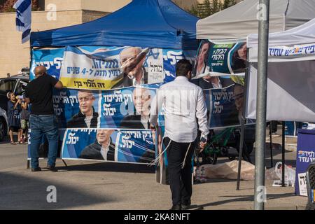 Un homme s'approche des stands de campagne près d'un centre de vote dans la ville de Harish, en faisant la promotion du parti Likoud (unité) du chef de l'opposition Benjamin 'Bibi' Nétanyahou. D'autres stands sur la photo font la promotion du parti « Yesh Atid » (il y a un avenir) du Premier ministre Yair Lapid, à droite, et du centre « Habayit Hayehudi » (la maison juive) d'Ayelet Shaked. À gauche de la photo, un enfant peut être vu crier dans un mégaphone Banque D'Images