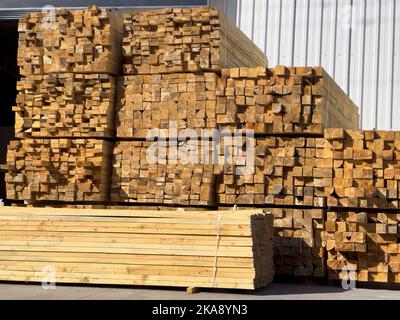 Les poutres en bois sont empilées les unes sur les autres devant l'entrepôt. Poutre en bois Banque D'Images